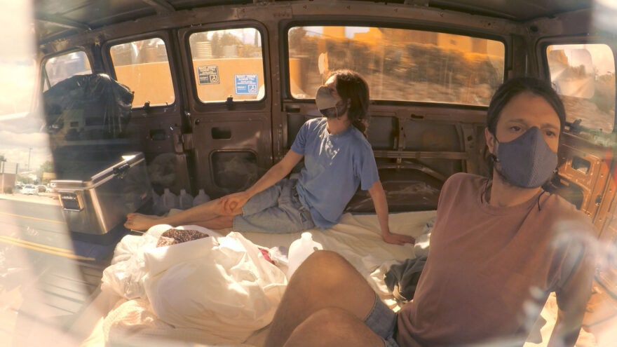 Two people wearing masks in a van