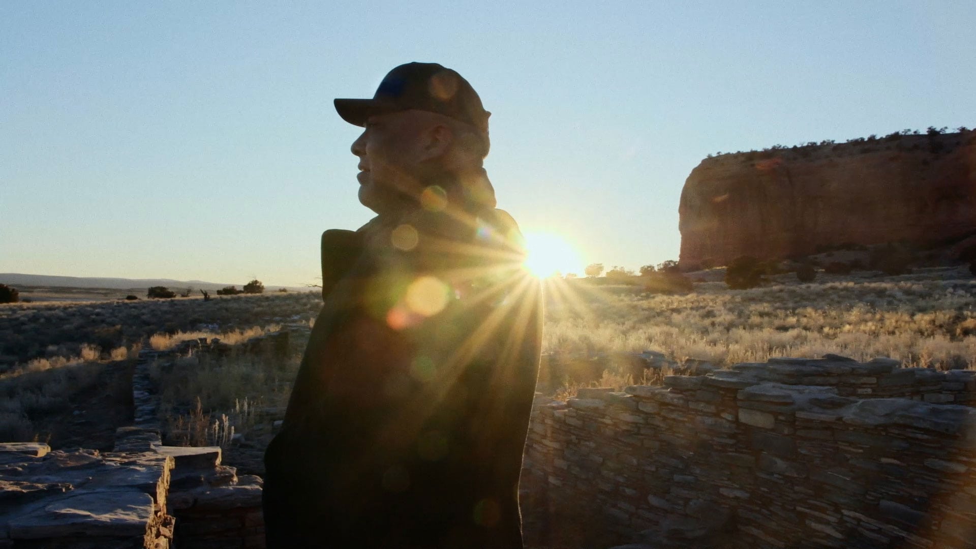 Man standing in desert with sunsetting behind him